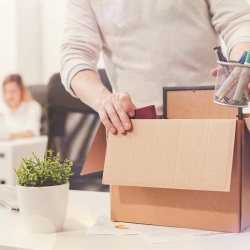 Nothing left behind. Attentive dedicated fired man packing his stuff in a box as he cleaning his workplace before leaving the office