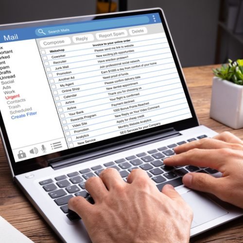 Close-up Of A Person's Hand Typing On Laptop Over Wooden Desk
