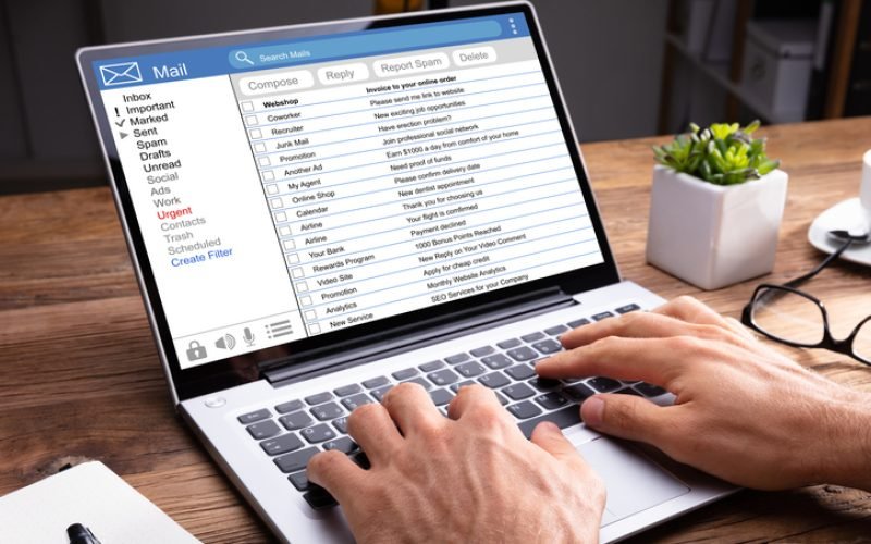 Close-up Of A Person's Hand Typing On Laptop Over Wooden Desk