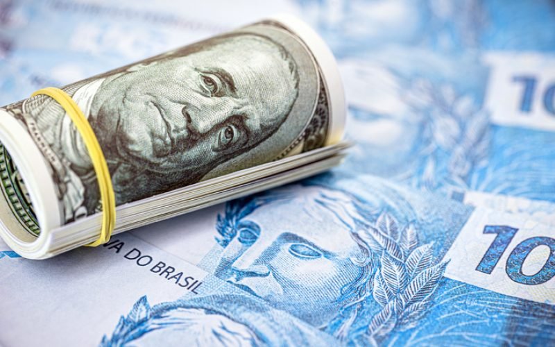 100 dollar banknote over 100 reais banknotes, point focus. Concept of high dollar against the Brazilian currency, Brazilian economic crisis