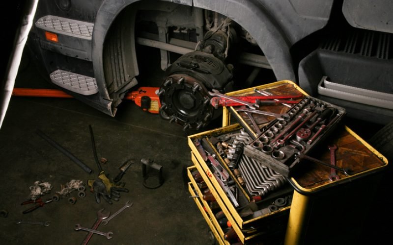 magic is being repaired en wheel in a workshop. All the necessary tools and equipment ready. The vehicle wheel hub removed and looks