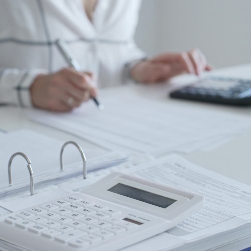 Close up of a calculator on financial documents, with an accountant taking notes, emphasizing accounting, finance, and tax preparation. Audit and taxes in business.