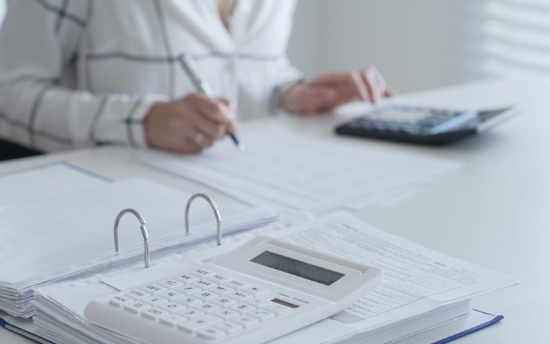 Close up of a calculator on financial documents, with an accountant taking notes, emphasizing accounting, finance, and tax preparation. Audit and taxes in business.