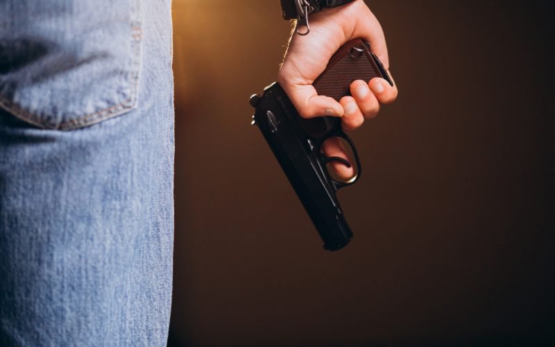 Handsome man actor posing in studio with weapon