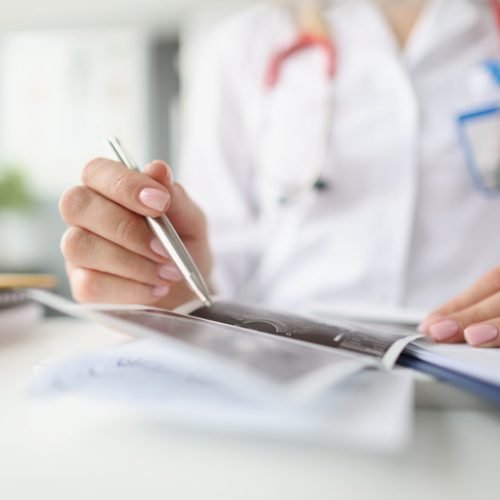 Hands of doctor holding and examining ultrasound scan. ultrasound diagnostics and diagnosis concept