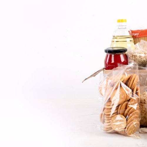 Food donation box of different products  on light background, top view. Food donations or delivery concept. Panorama, banner, copy space