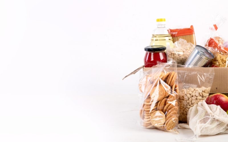 Food donation box of different products  on light background, top view. Food donations or delivery concept. Panorama, banner, copy space