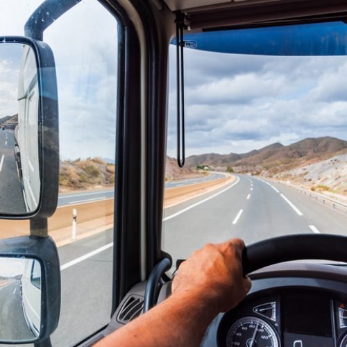 View from the driving position of a truck of the rearview mirror and the empty highway.