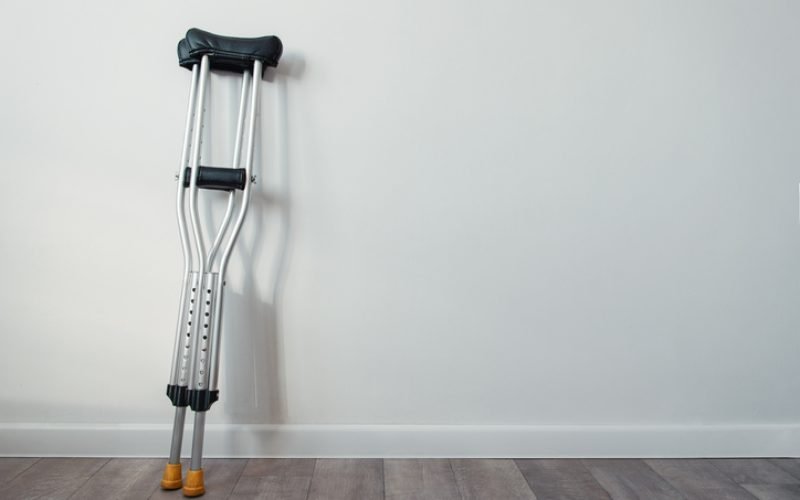 crutches stand near a white wall with copyspace