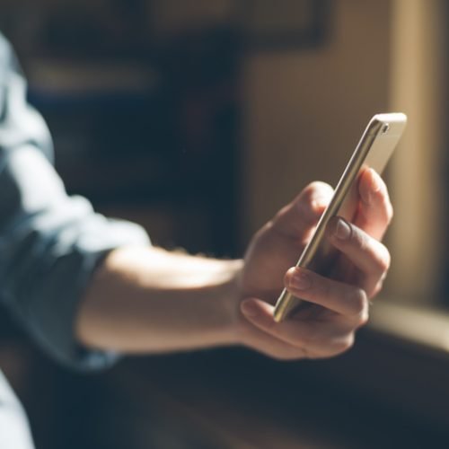 Hipster using a touch screen smart phone hands close up, vintage colors